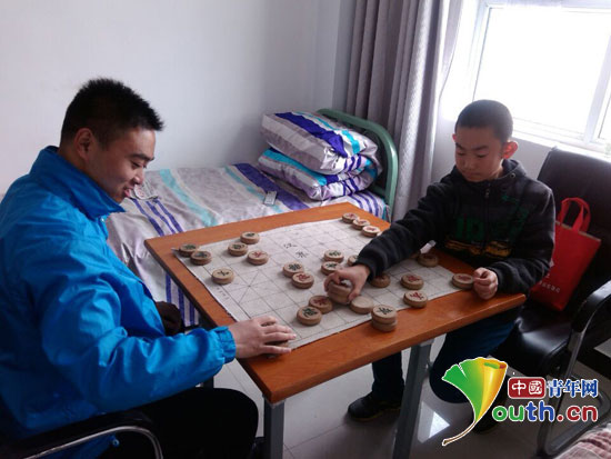木壘縣志愿者與新溝村兒童下象棋。