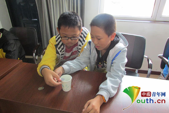 參加周末課堂活動(dòng)的留守兒童在做“硬幣存水”科普實(shí)驗(yàn)。哈爾濱工程大學(xué)支教團(tuán)供圖