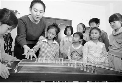10月11日，在河北省邢臺市橋東區(qū)三義廟社區(qū)“兒童之家”，小女孩張佳欣在邢臺華藝音樂培訓(xùn)機(jī)構(gòu)教師楊賽男的指導(dǎo)下感知古箏。